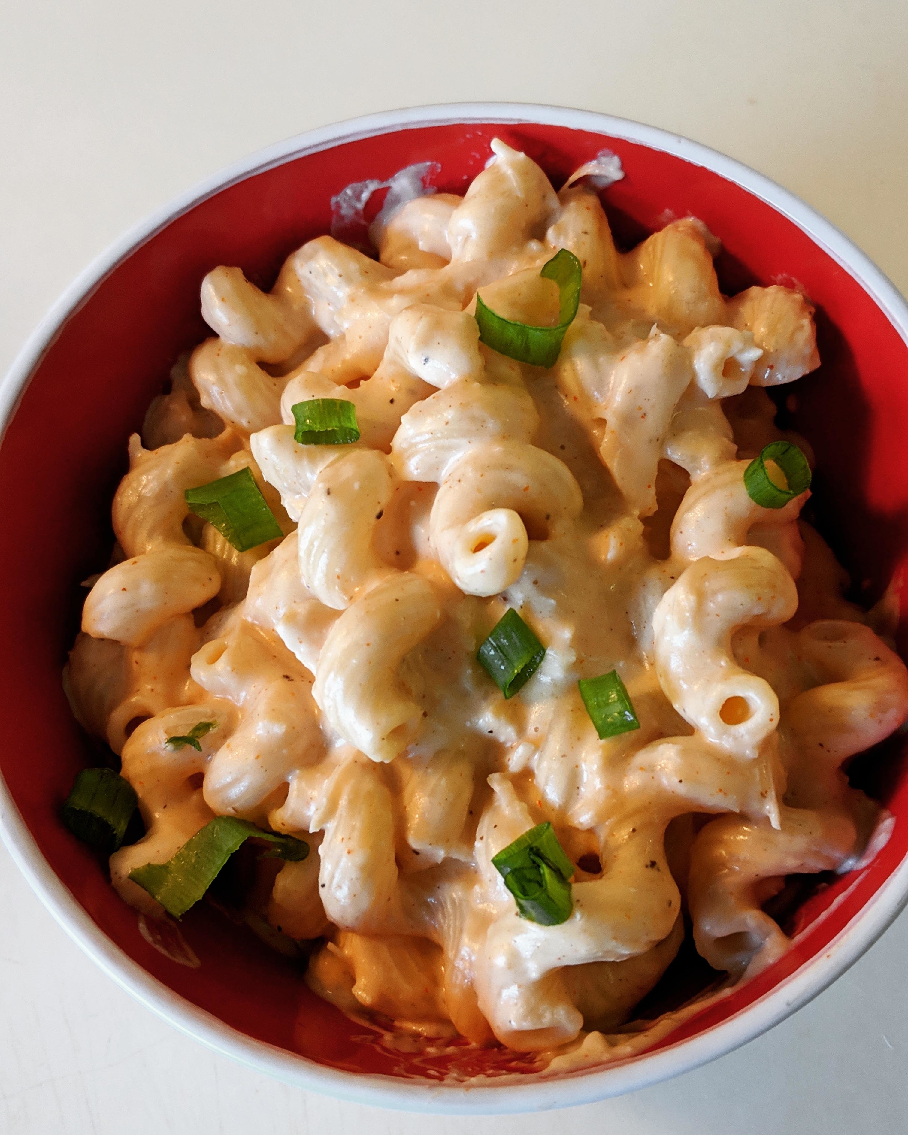 Bowl of macaroni and cheese garnished with green onions