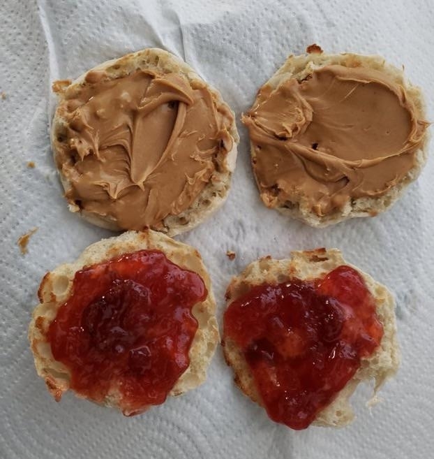 Four open-faced sandwich halves with peanut butter on top two, jelly on bottom two, on a napkin