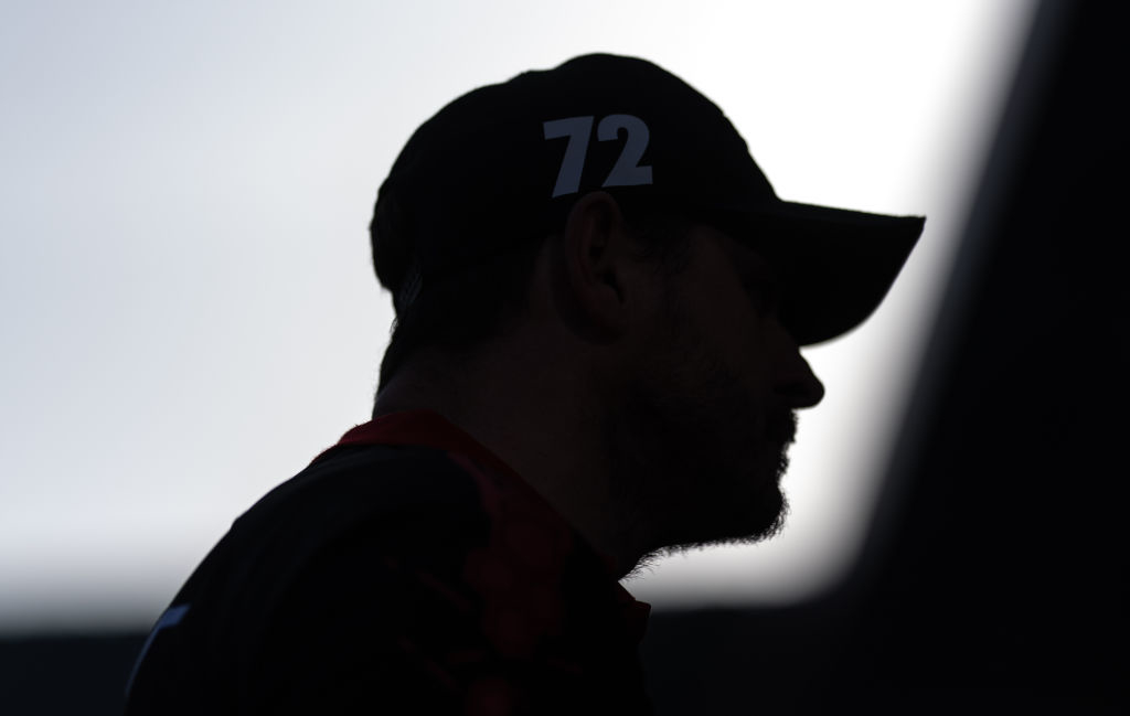 Silhouette of an unidentifiable person with a cap labeled &#x27;72&#x27; amidst a dimly lit setting