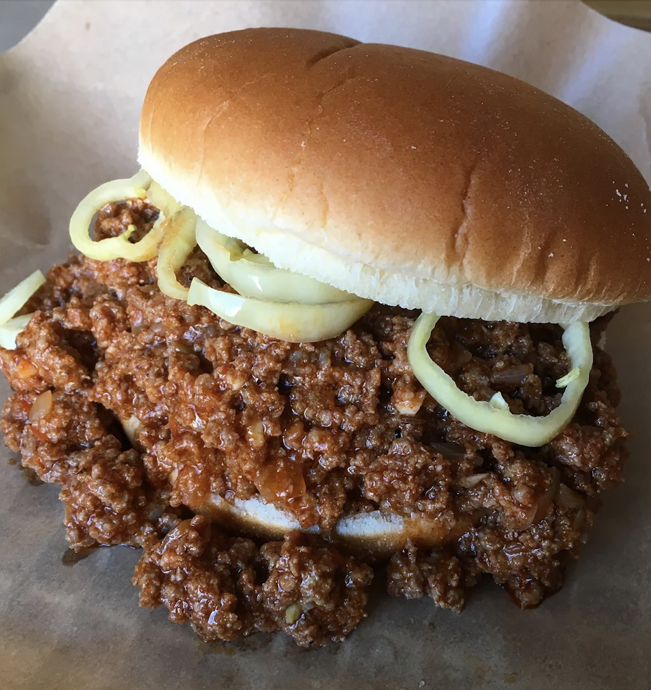 A sloppy joe sandwich with ground beef and onions on a bun