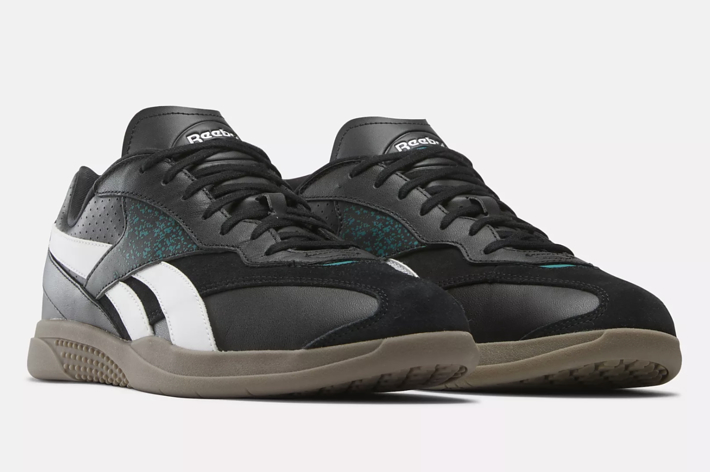 A pair of Reebok sneakers with a classic silhouette featuring black, white and speckled teal accents