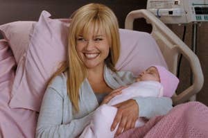 Reese Witherspoon sitting in a hospital bed and smiling while holding a baby as Kate in Four Christmases