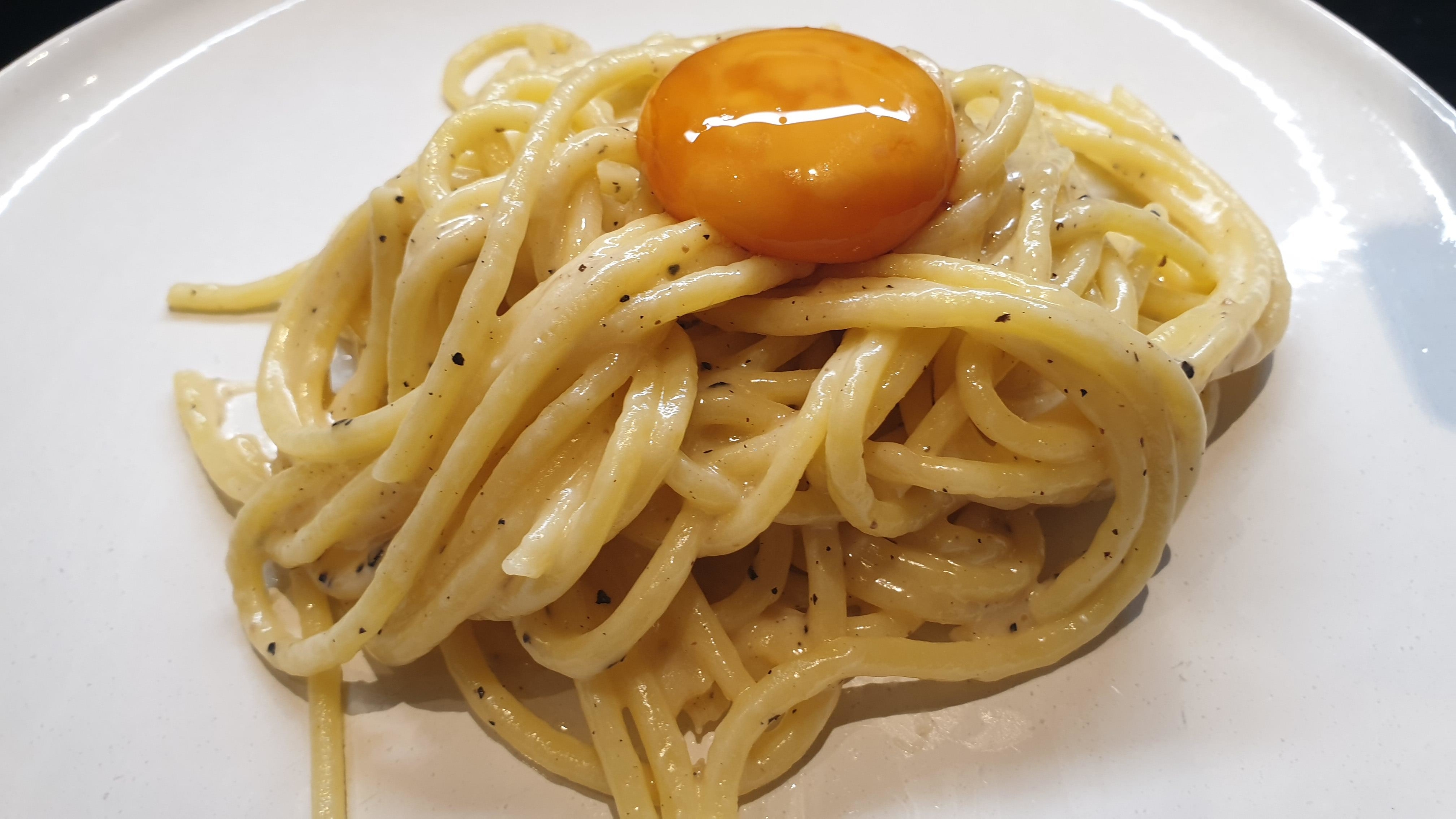 Plate of spaghetti topped with an egg yolk