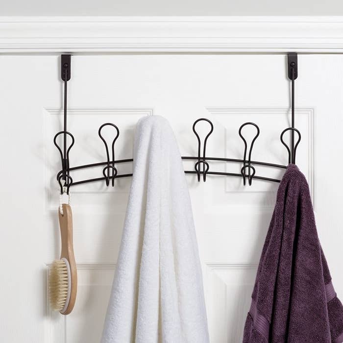 Over-the-door hook rack with towels and a brush