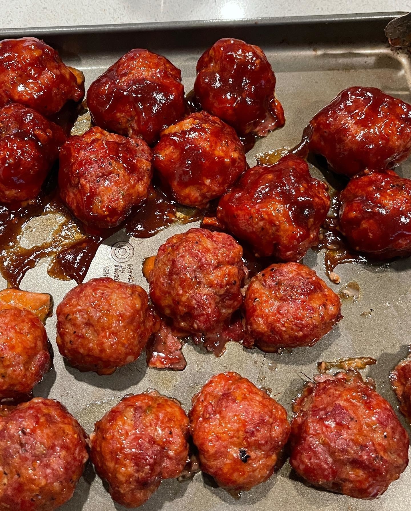 A tray of freshly cooked meatballs with glaze