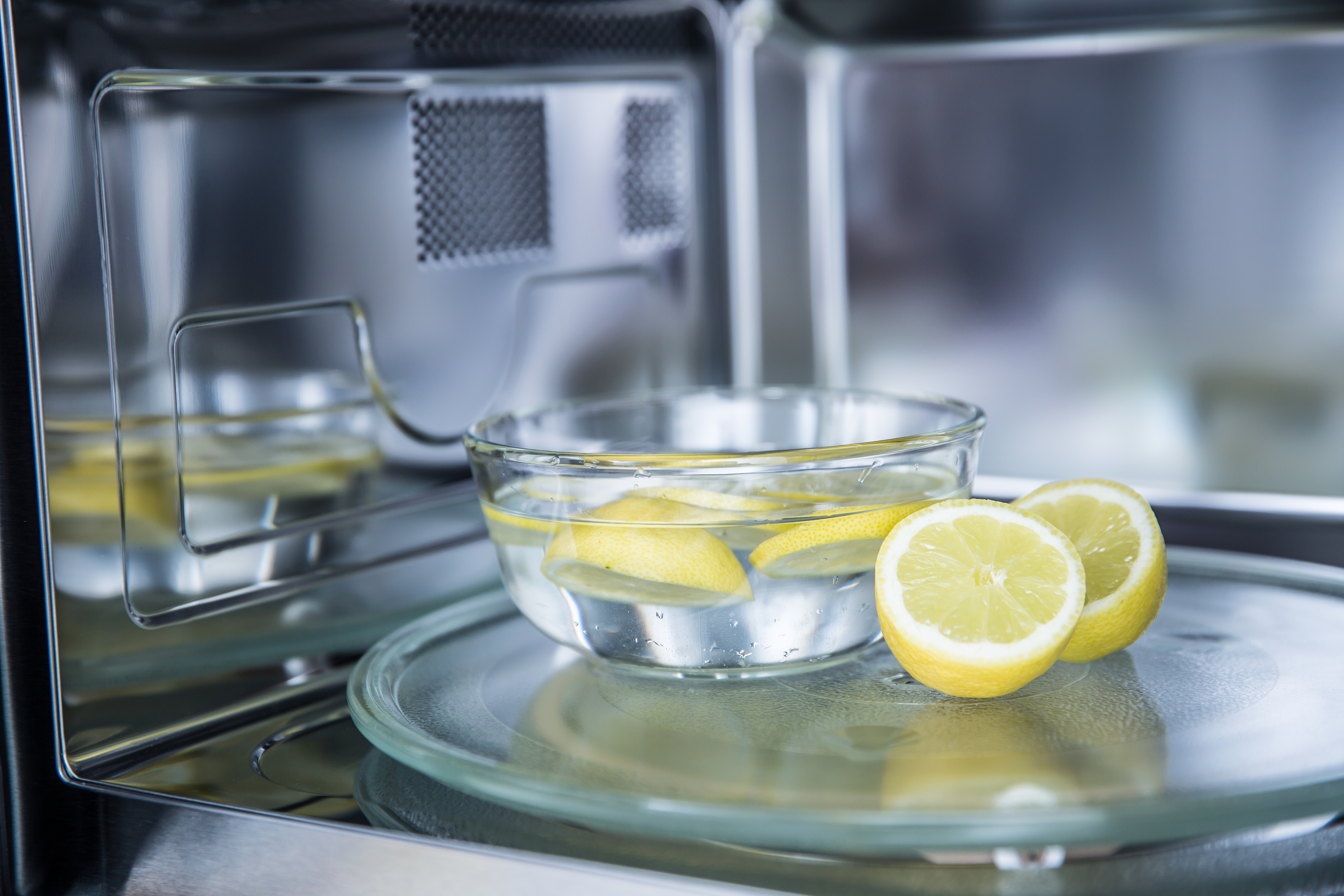 Bowl of water with lemon slices inside a microwave, suggesting a cleaning hack