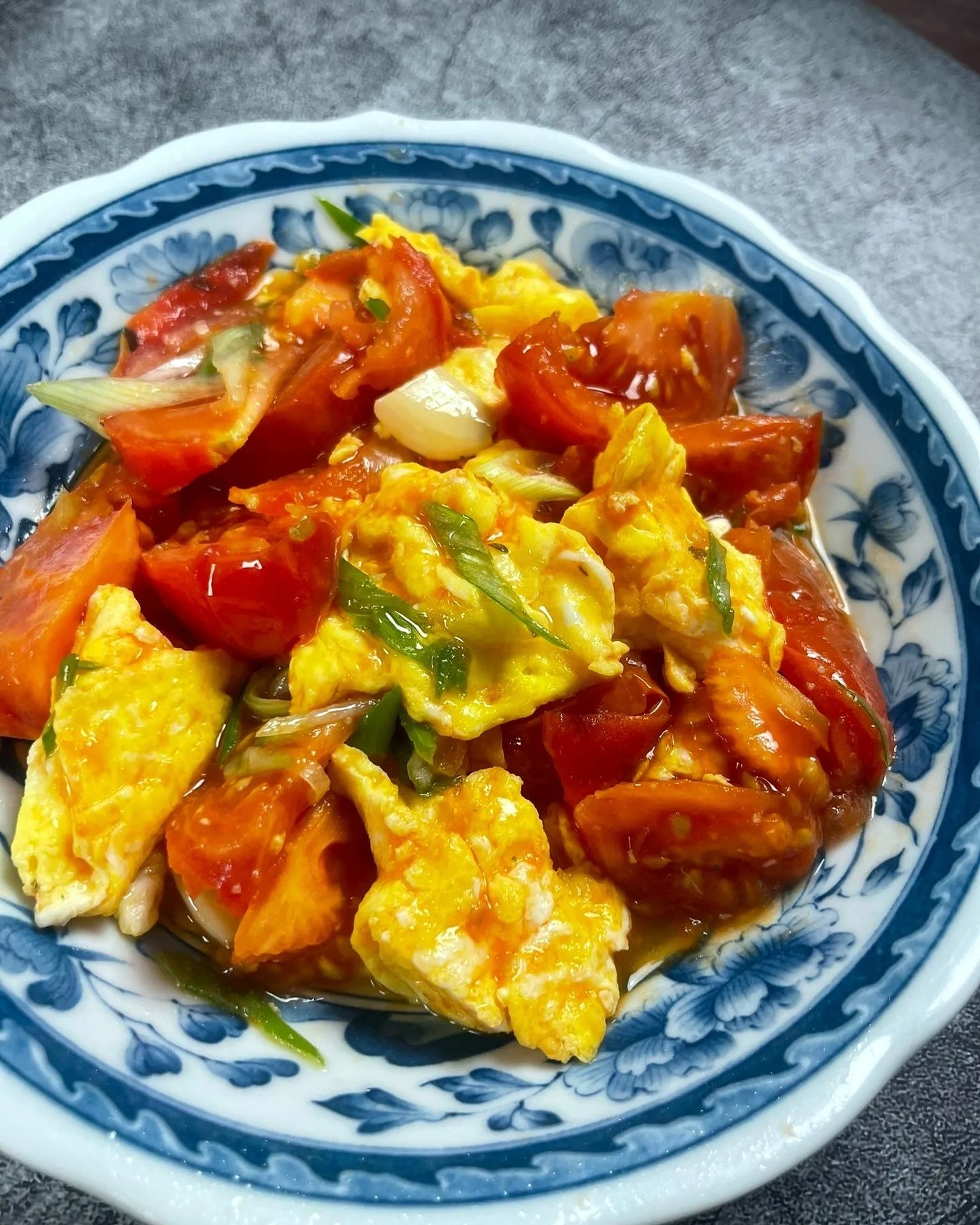 Stir-fried dish with tomatoes and eggs in a blue-patterned bowl