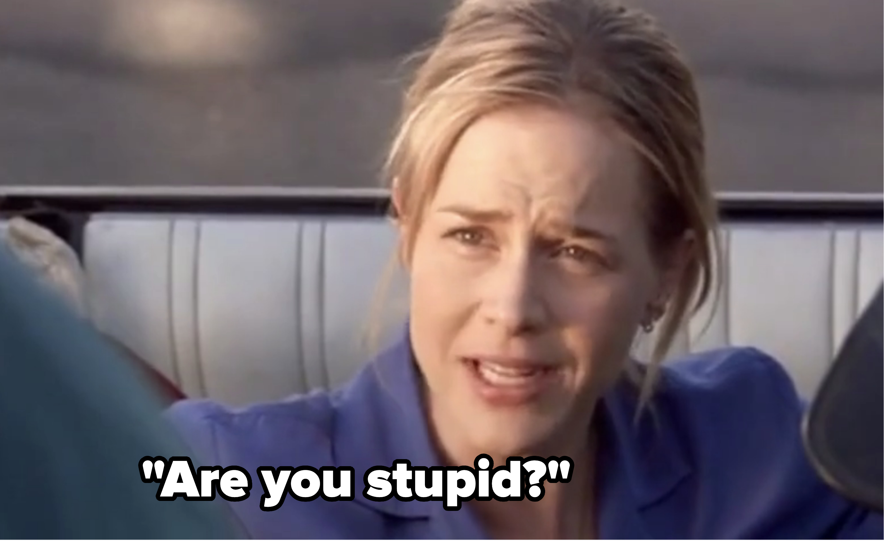 Woman with blonde hair wearing a blue shirt, looks concerned, in a car scene