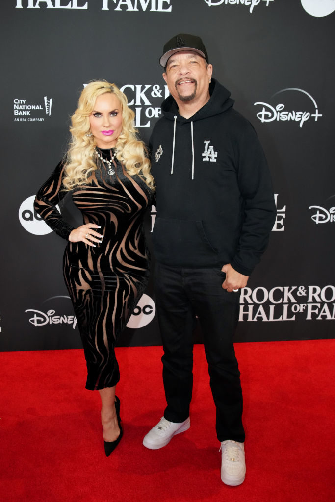 Coco, in a striped dress and heels, and Ice-T, in a hoodie and cap, posing together on the red carpet