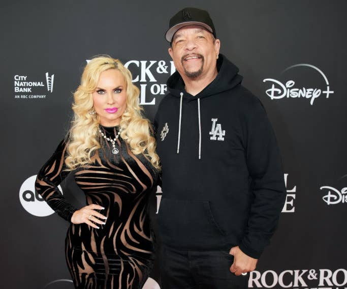 Coco, in a striped dress and heels, and Ice-T, in a hoodie and cap, posing together on the red carpet