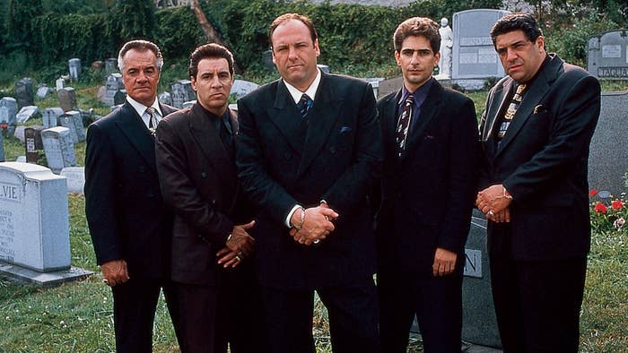 Four men in suits stand solemnly at a cemetery. They are characters from a TV show
