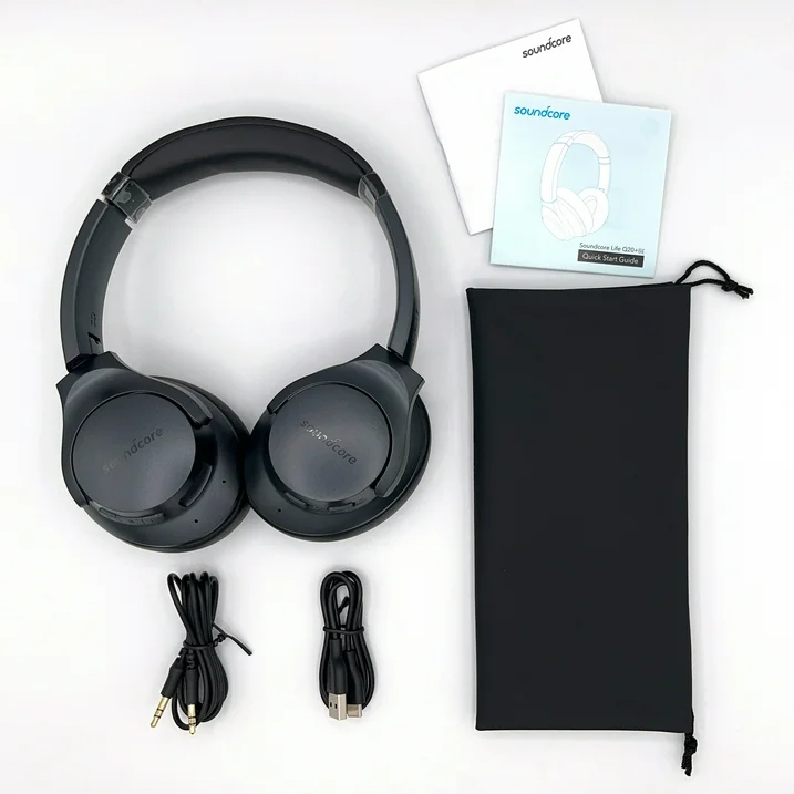 Black over-ear headphones with accessories and a carrying pouch laid out on a plain surface
