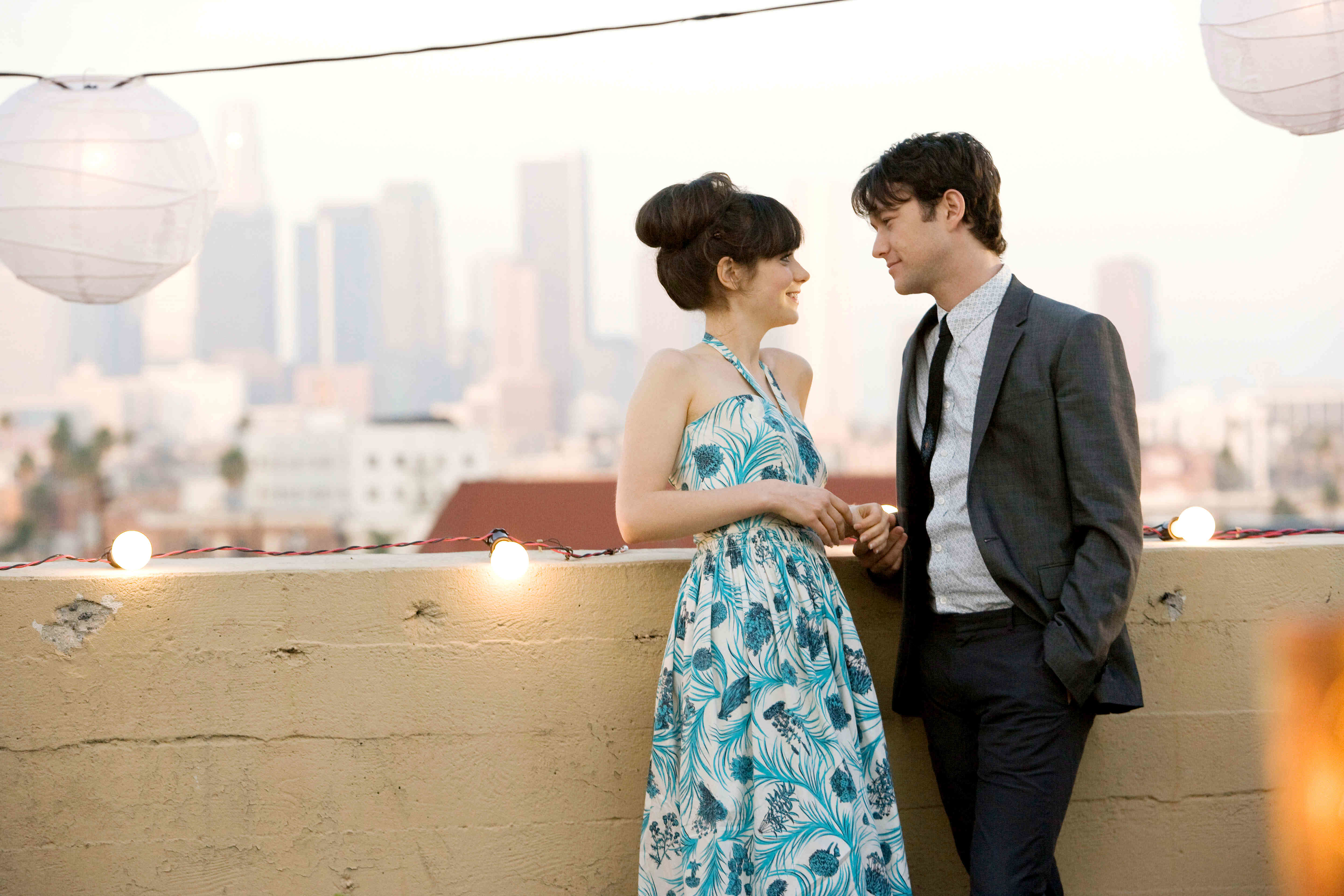 Two characters from the movie &quot;500 Days of Summer&quot; sharing a moment on a rooftop with city skyline in the background