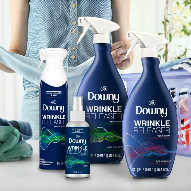 Person standing by a table holding a shirt with three Downy Wrinkle Releaser products displayed in front