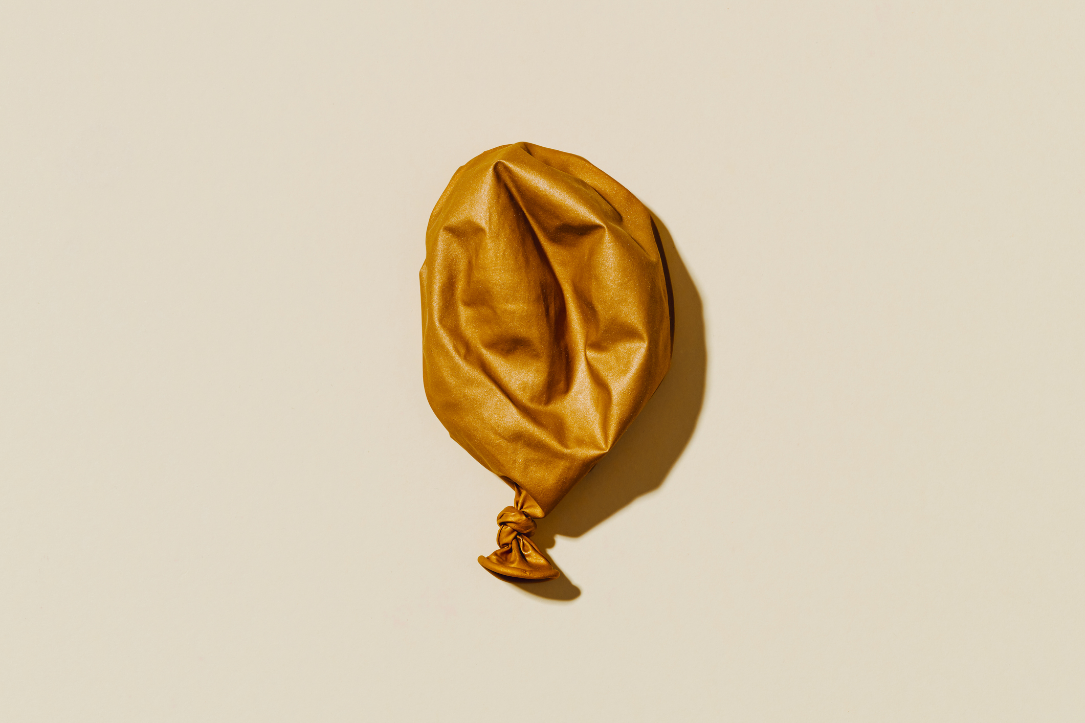 A deflated gold balloon on a plain background, related to themes of romance and relationships