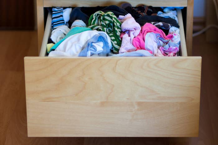 Open drawer filled with assorted unorganized clothing items