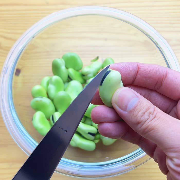 手がそら豆をむいている写真です。