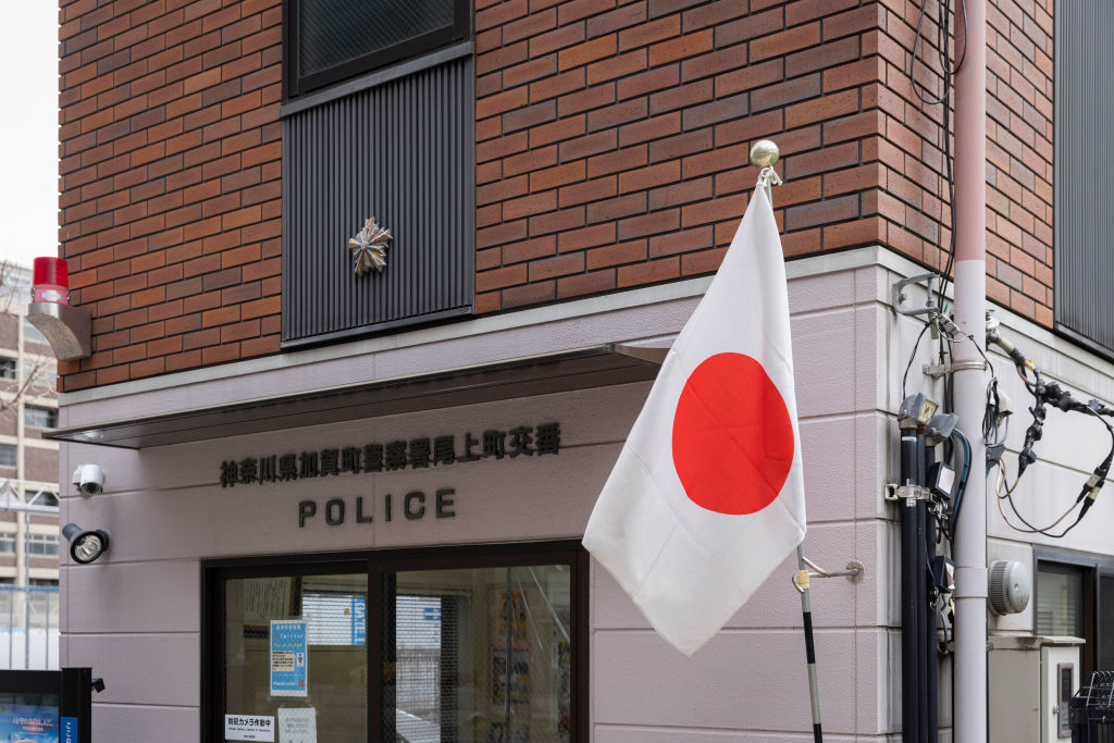 A Japanese flag hangs in front of a police station with signage in Japanese characters