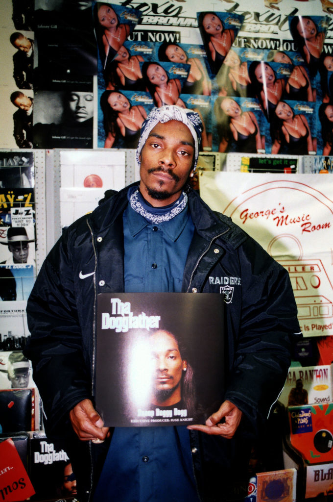 Snoop Dogg holding his album &quot;Tha Doggfather&quot; in a music store with posters in the background