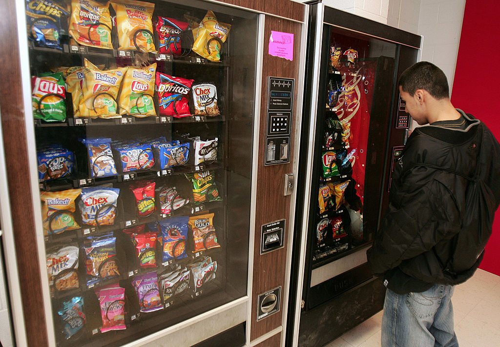 Person standing in front of a snack vending machine, considering options