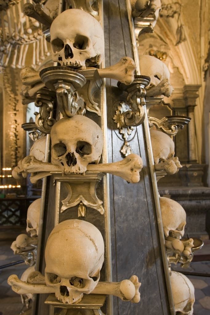 Decorative column adorned with sculpted skulls and bones in an ornate setting