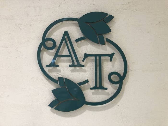 壁に取り付けられた「AT」のモノグラムと葉のデザインのロゴ。
