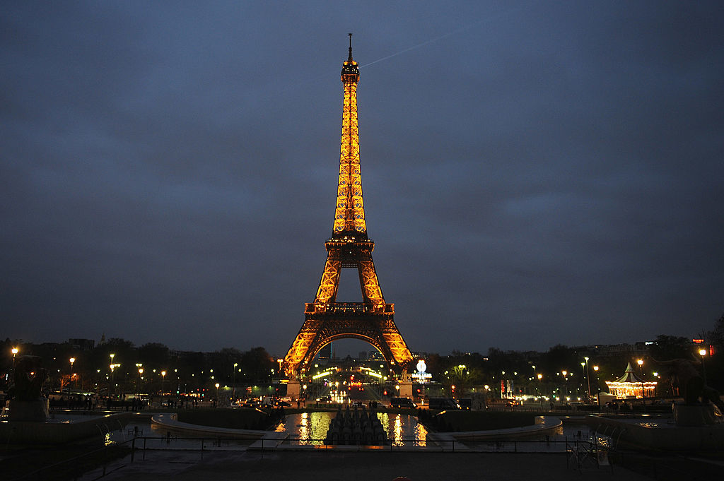 Illuminated Eiffel Tower at twilight with surrounding city lights