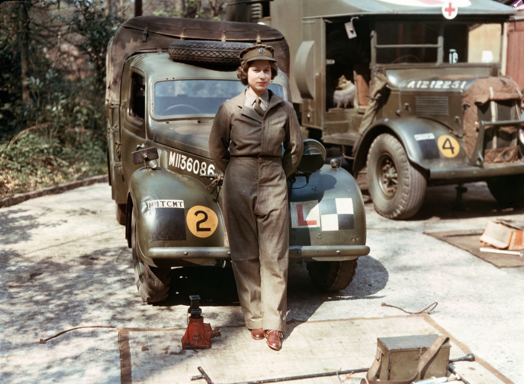 Queen Elizabeth II in military uniform during World War II, standing beside an army ambulance