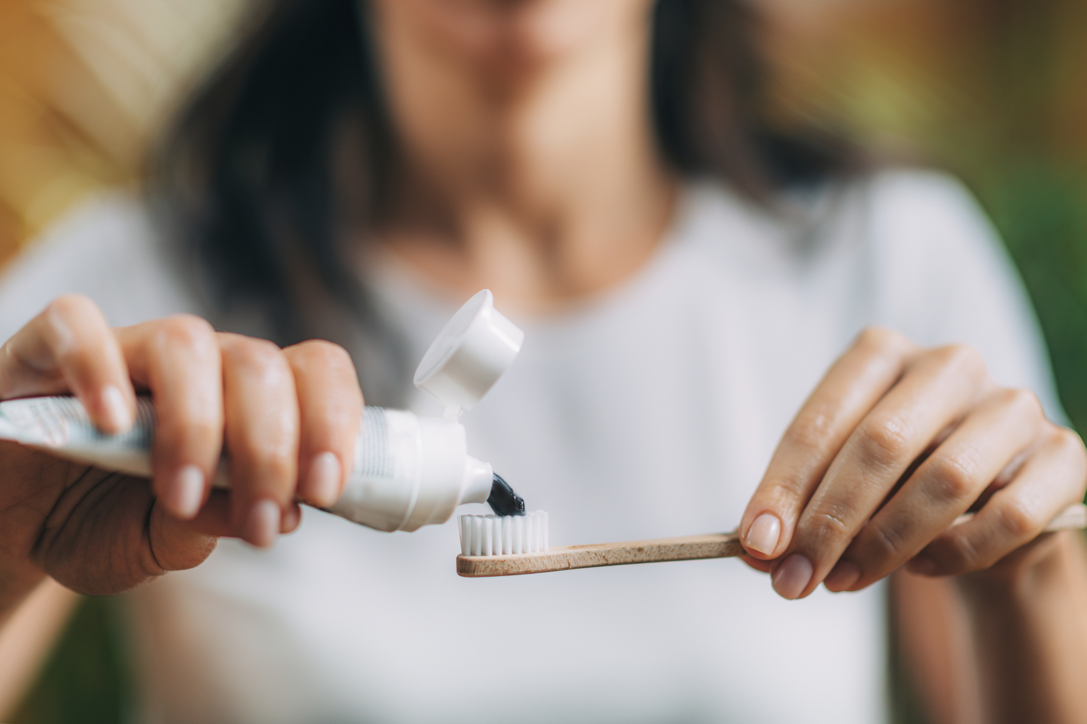 Person applies toothpaste to a toothbrush, close-up on hands and toothpaste tube