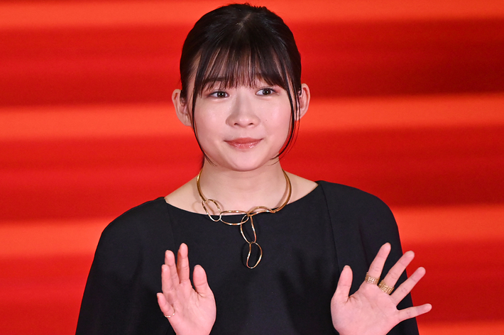 ドレスアップした女性がレッドカーペットで手を振っている。