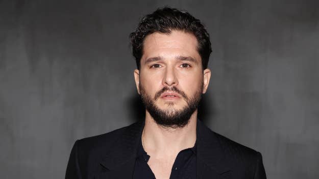 Kit Harington in a dark suit looking at the camera. Expresses a serious demeanor