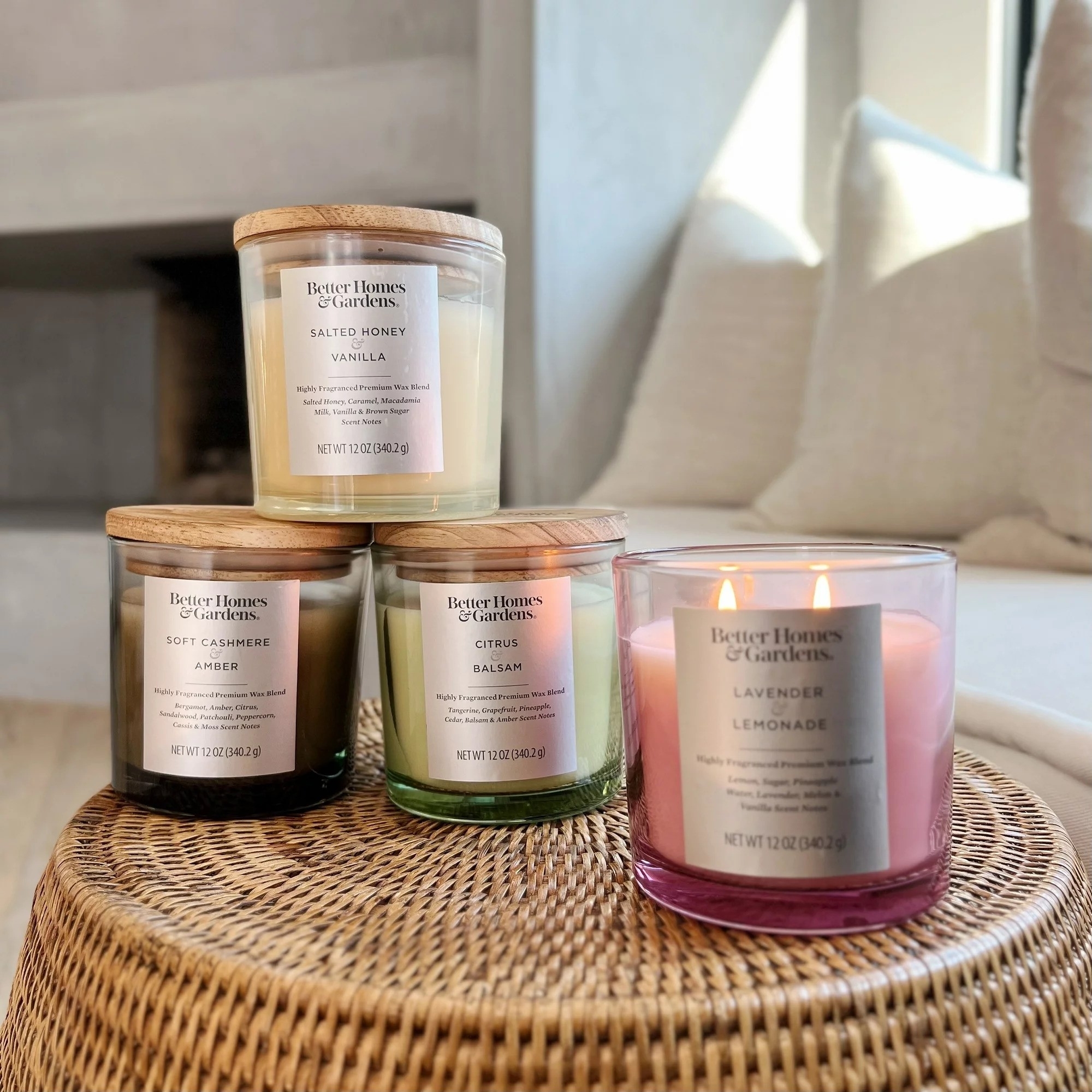 Four Better Homes and Gardens scented candles on a wicker table, with varying scents including Lavender Lemonade