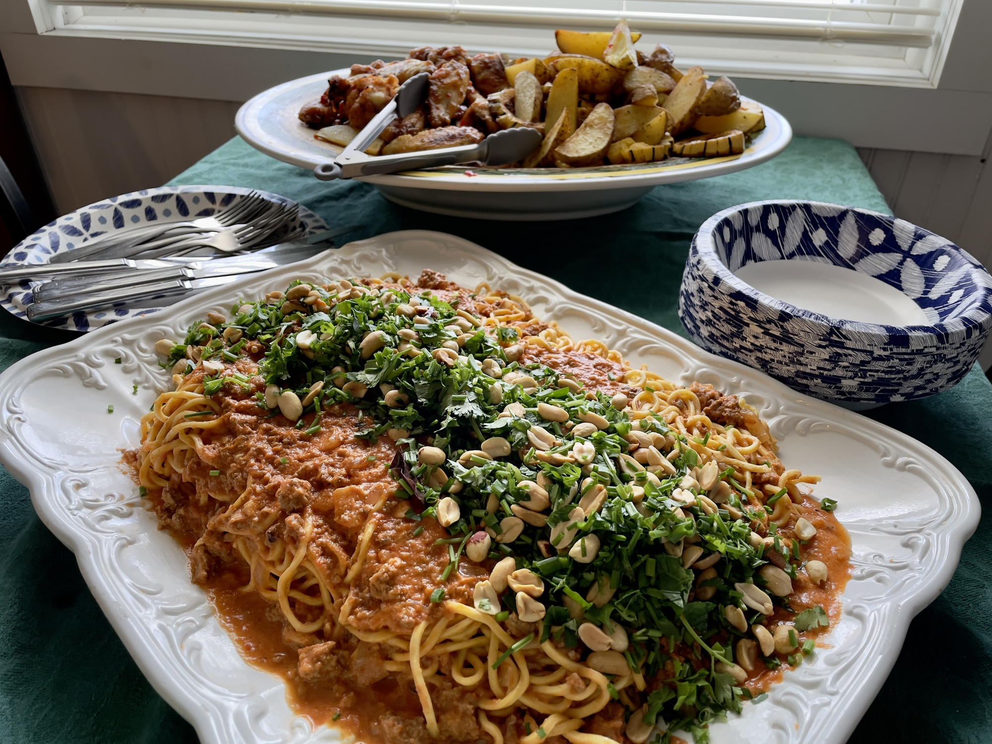 A plate of spaghetti with tomato sauce, topped with herbs and nuts, served with side dishes in the background