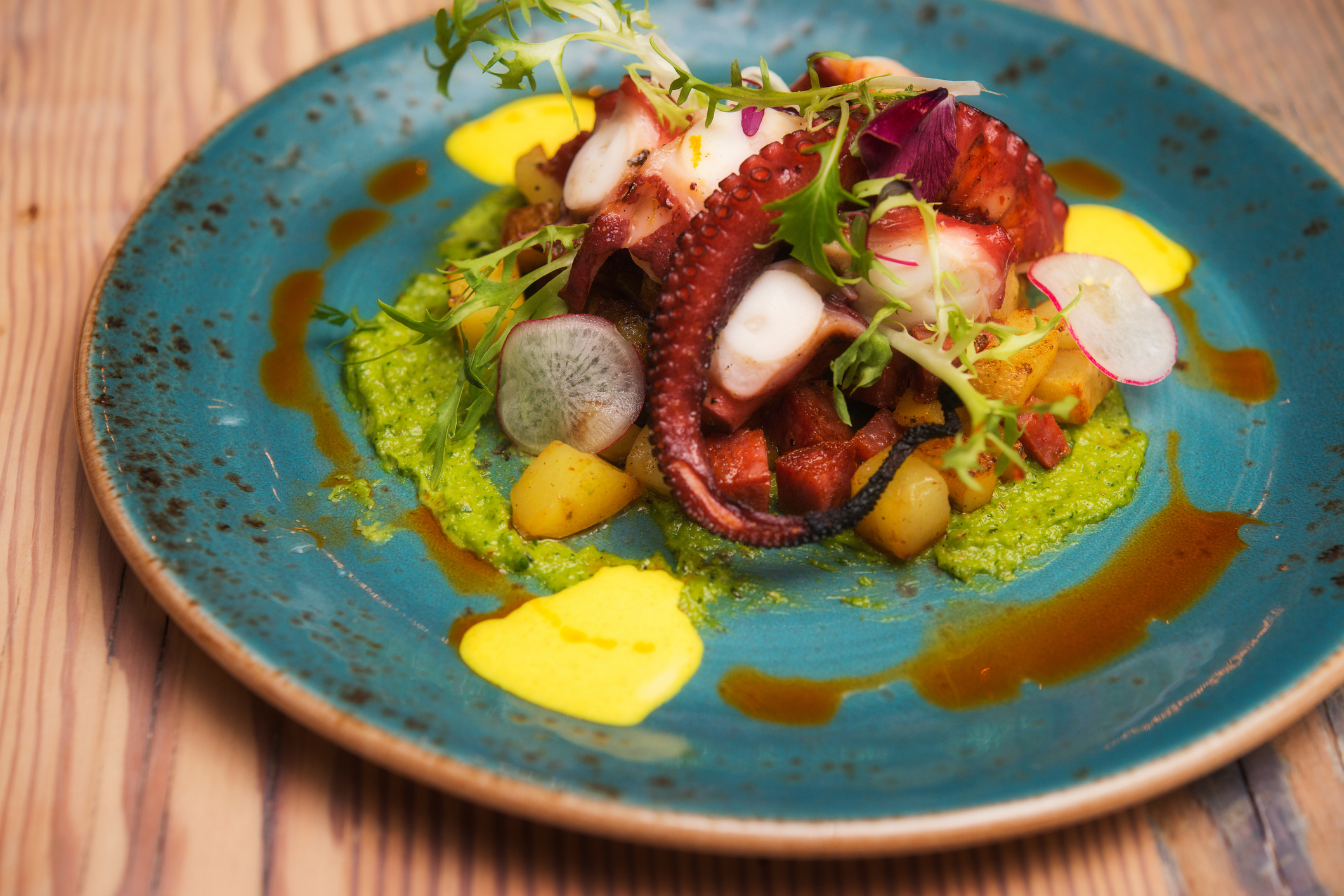 Grilled octopus served with vegetables on a blue plate
