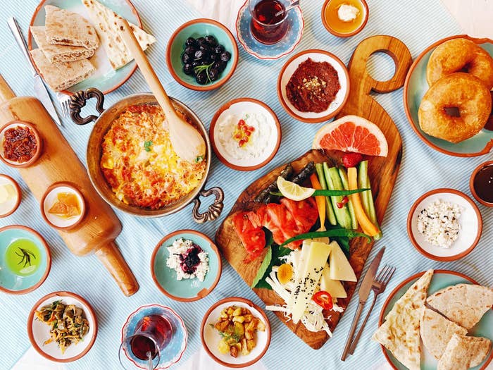 Assorted breakfast items including eggs, bread, cheese, and tea on a table