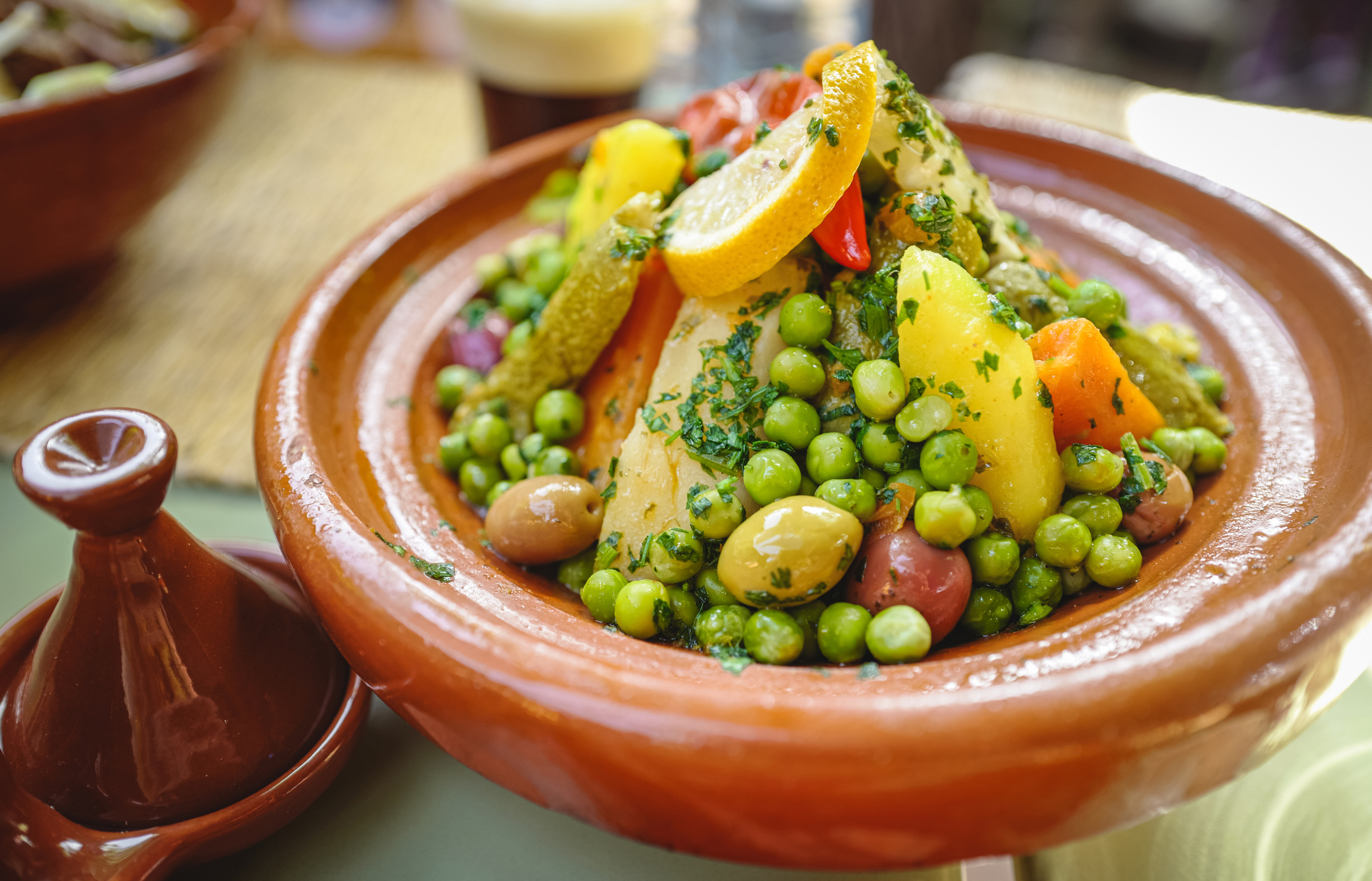 Traditional Moroccan tagine with vegetables and garnish on a table
