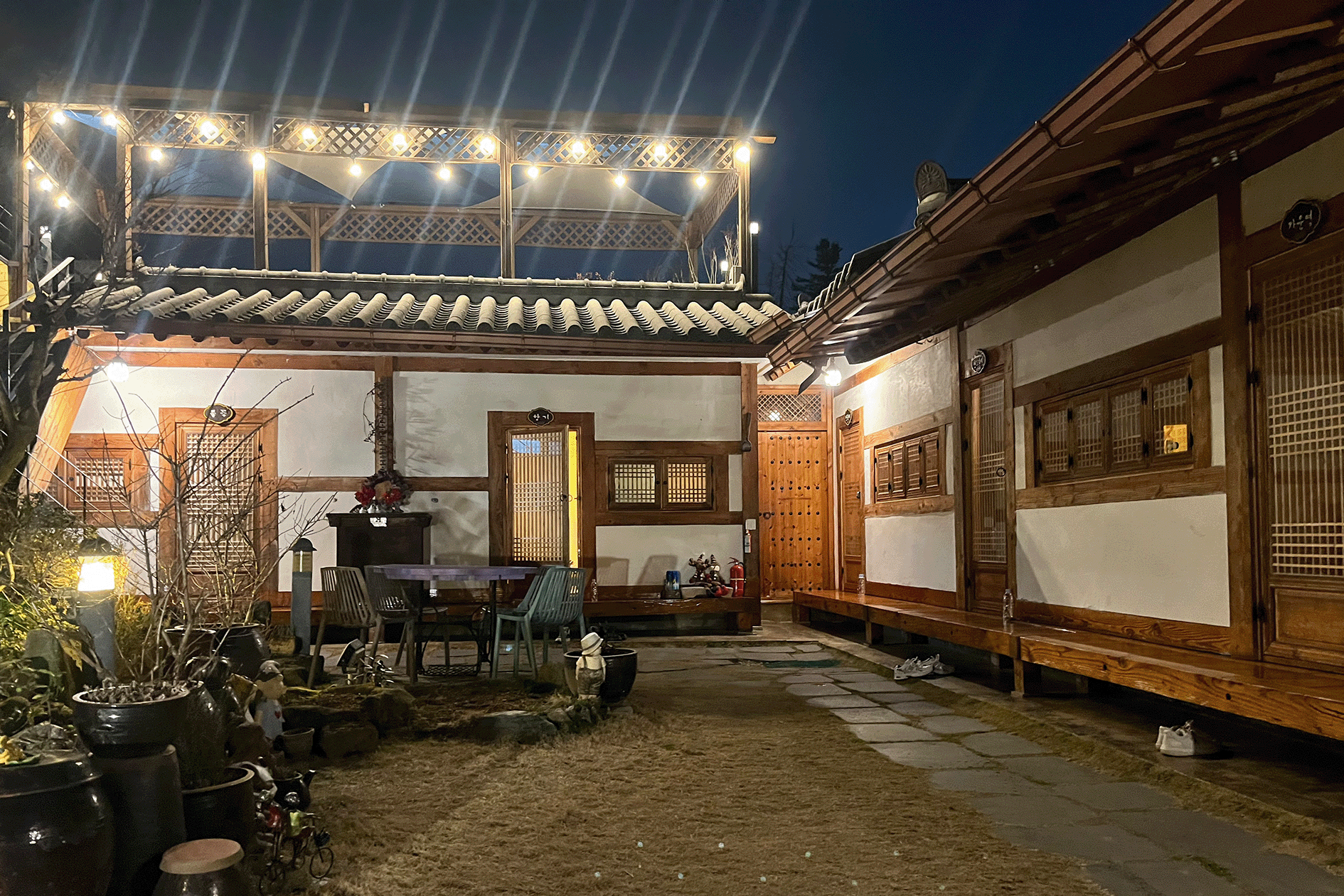 Traditional Korean hanok house at night with illuminated windows and outdoor sitting area