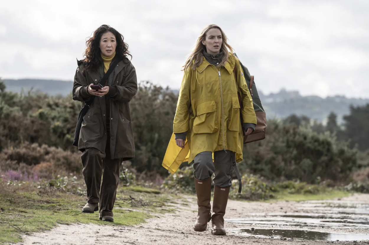Eve Polastri and Villanelle walk together in a rural setting, both wearing long coats and boots in &quot;Killing Eve.&quot;