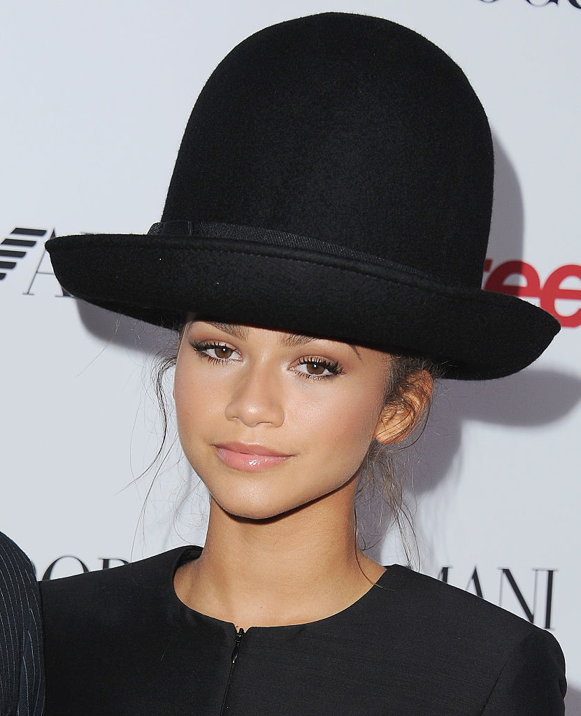 Zendaya in a black outfit and large brimmed hat at an event