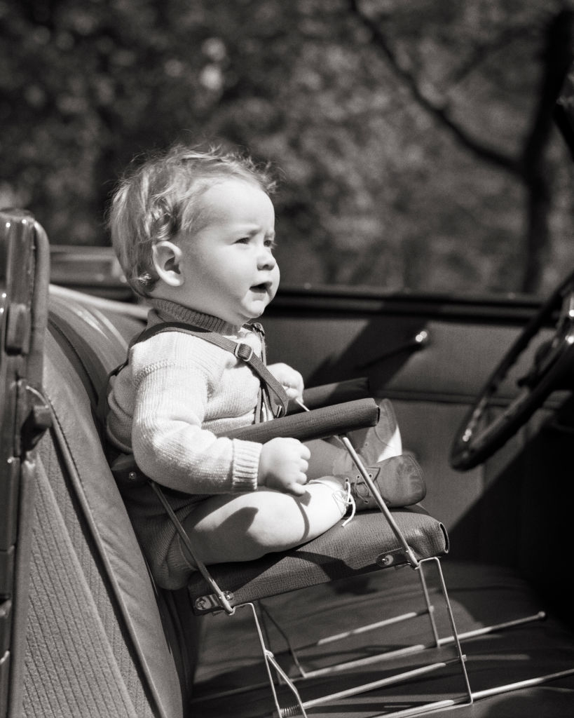 Toddler in a vintage car seat that faces forward in the front seat