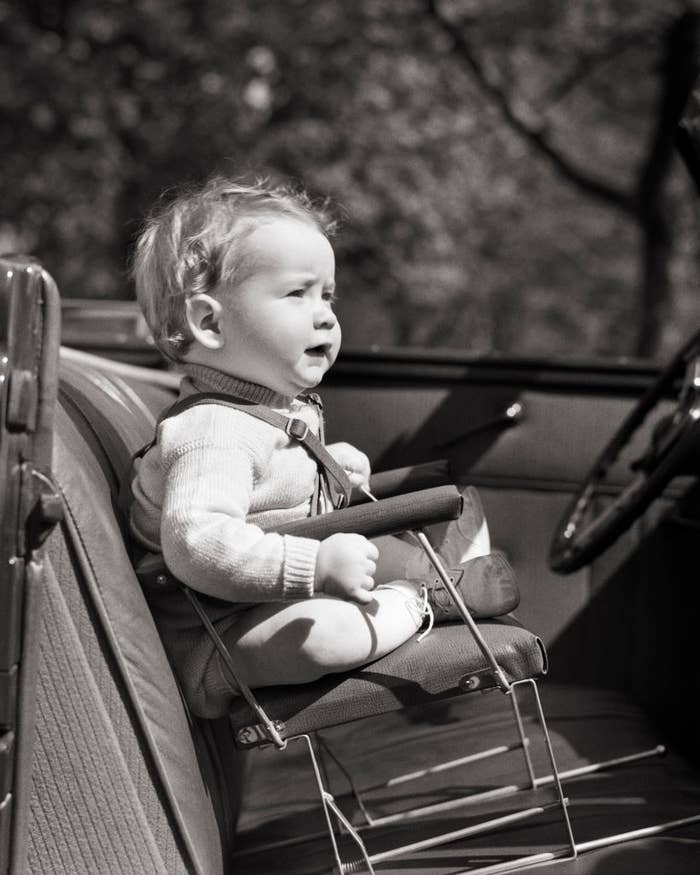 Toddler in a vintage car seat, mouth open as if talking or singing
