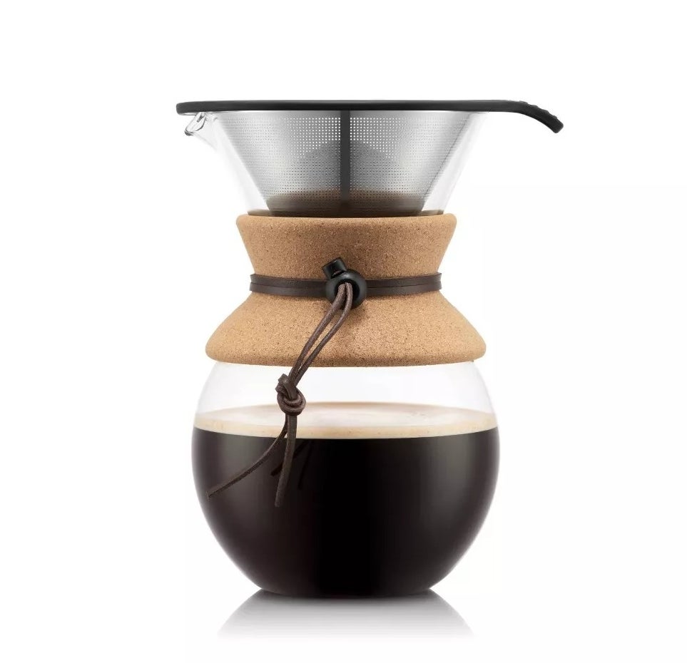 A modern glass pour over coffee maker with a cork band and handle, containing brewed coffee