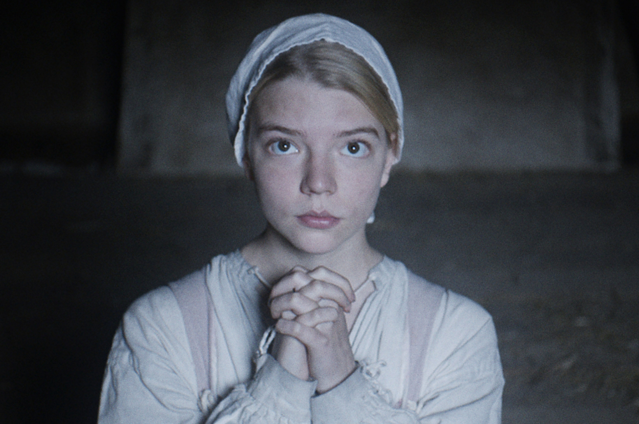 Anya Taylor-Joy as Thomasin in The Witch, hands clasped in prayer, wearing a plain bonnet