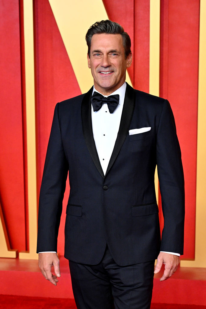 Jon in a tuxedo with bow tie poses on a red carpet