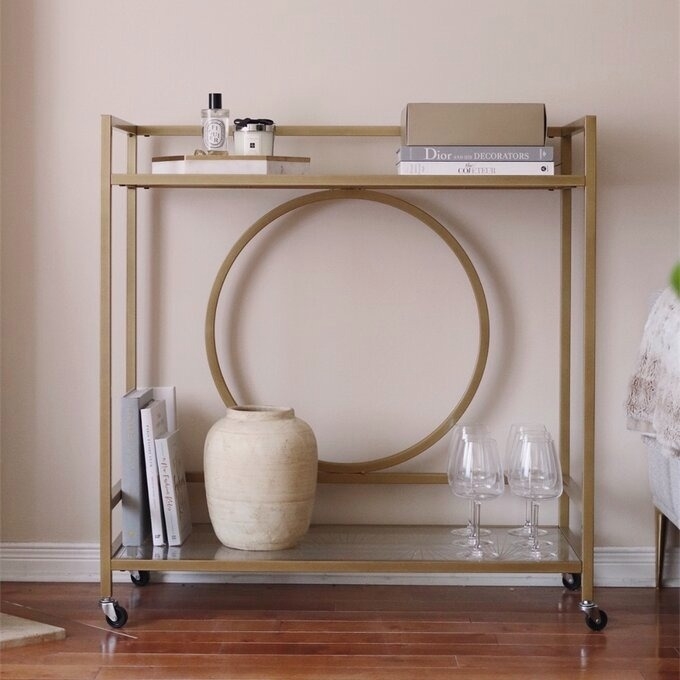 A minimalist bar cart with books, a decorative vase, and glasses, reflecting a simple, elegant home style