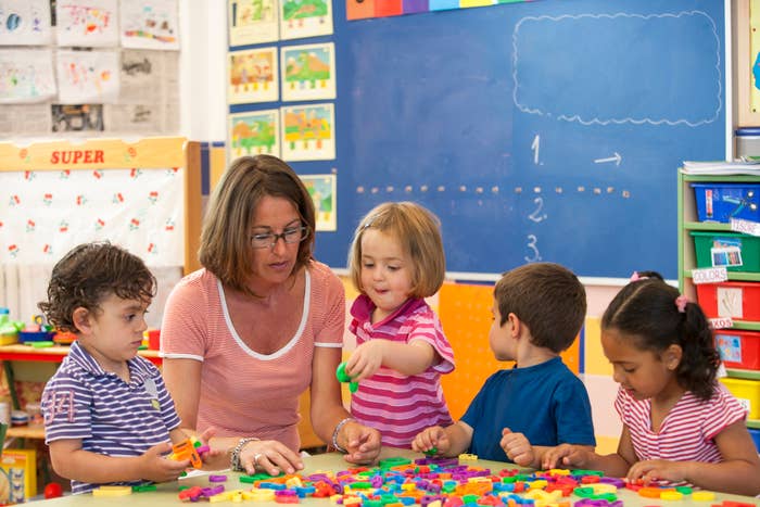 Teacher and children engaging with colorful blocks on a table in a classroom setting