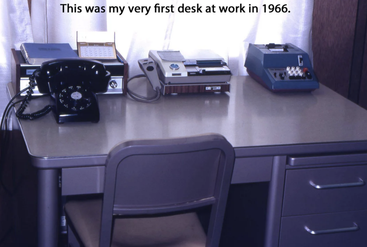 Vintage office desk from 1966 with a rotary phone, typewriter, and telex machine. Text overlay: &quot;This was my very first desk at work in 1966.&quot;
