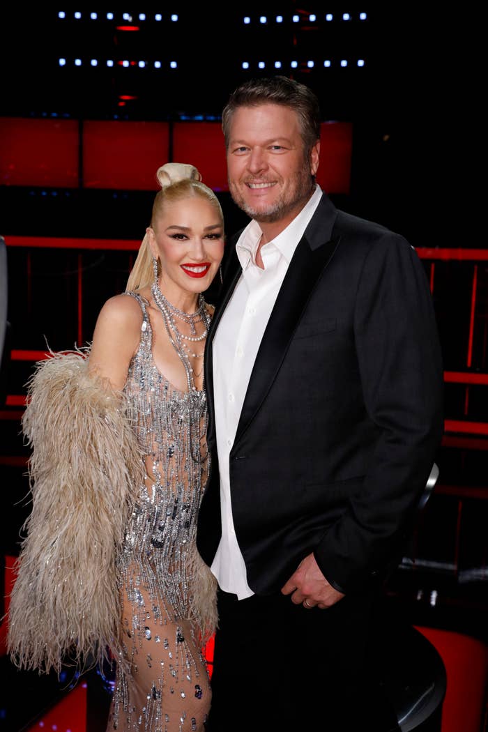 Gwen Stefani and Blake Shelton posing together, Stefani in a fringed, sparkly dress, Shelton in a suit without a tie