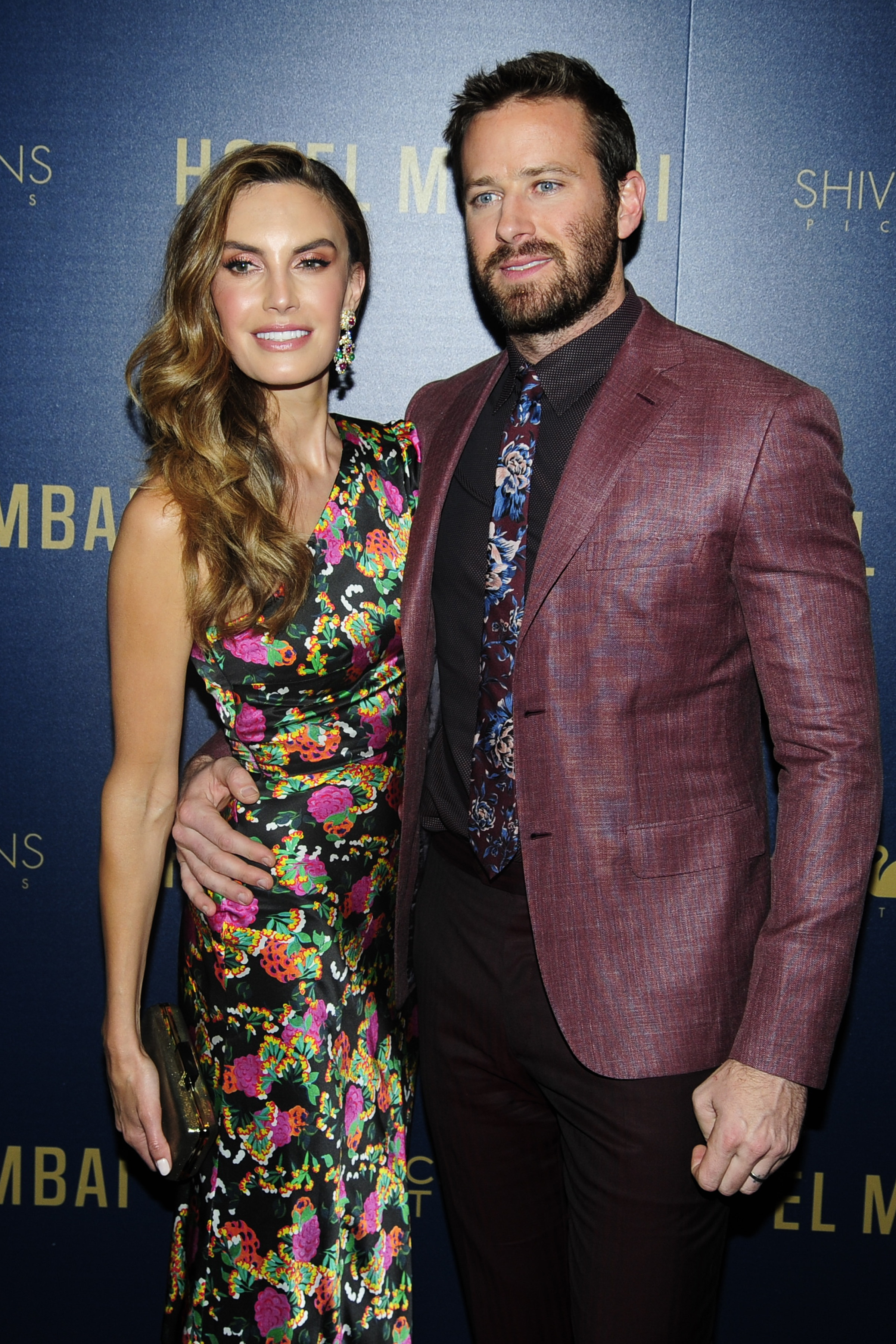 Elizabeth Chambers in a floral dress and Armie Hammer in a maroon suit at an event