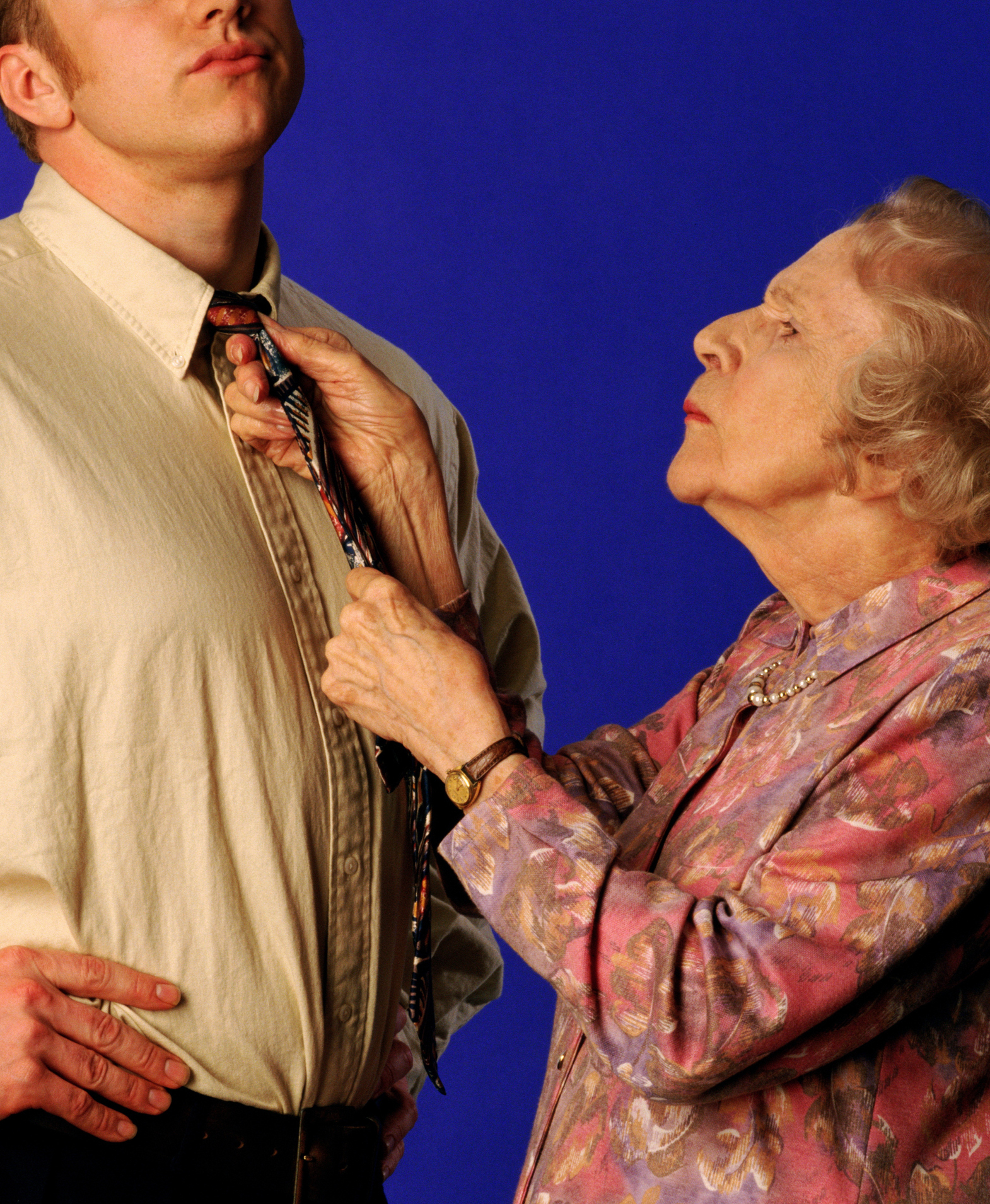 older woman adjusting a younger man&#x27;s tie